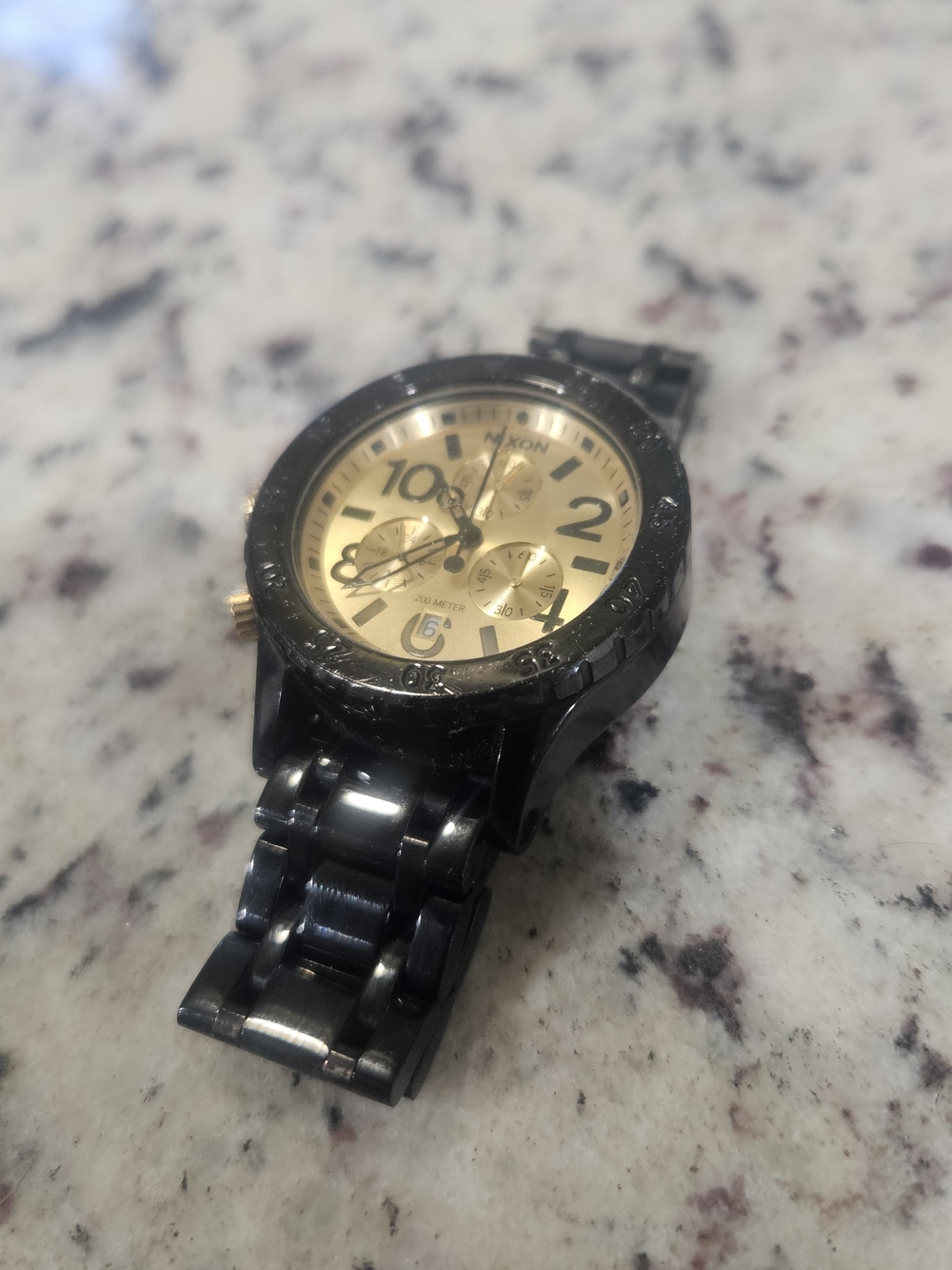 Nixon Menโs Black and Gold Chronograph Bracelet Watch